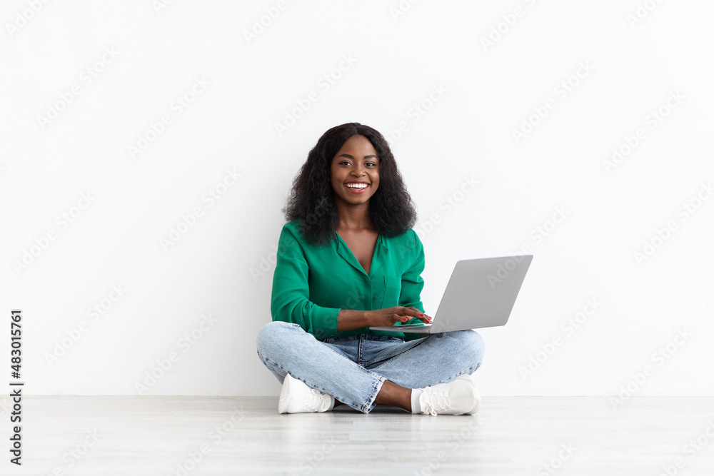 Naklejka premium Happy pretty black woman with laptop on white