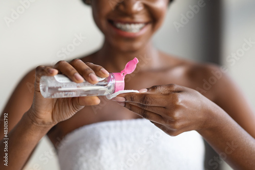 Unrecognizable black lady using micellar water, closeup