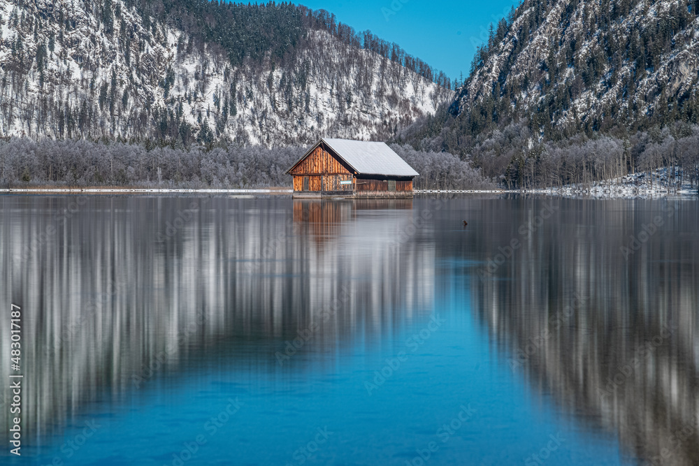 Dreamlike Winter wonderland in Almtal, Salzkammergut. Frozen Trees, snowcaped mountains, crystal clear Almsee with wooden boathouse, Totes Gebirge, Upper Austria