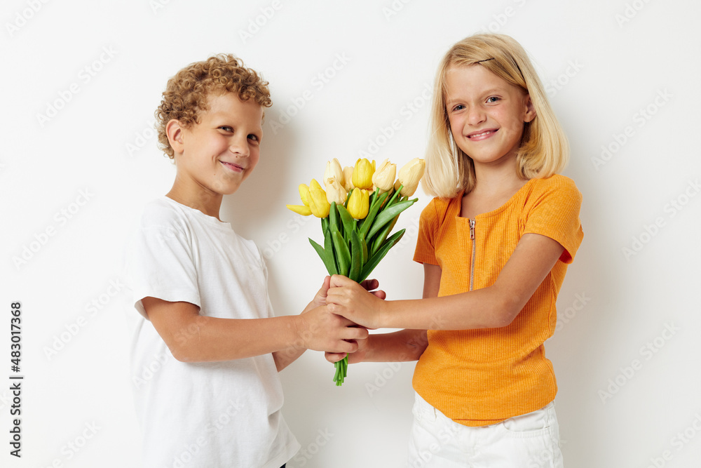Boy and girl with a bouquet of flowers gift birthday holiday childhood light background Boy and girl with a bouquet of flowers gift birthday holiday childhood light background