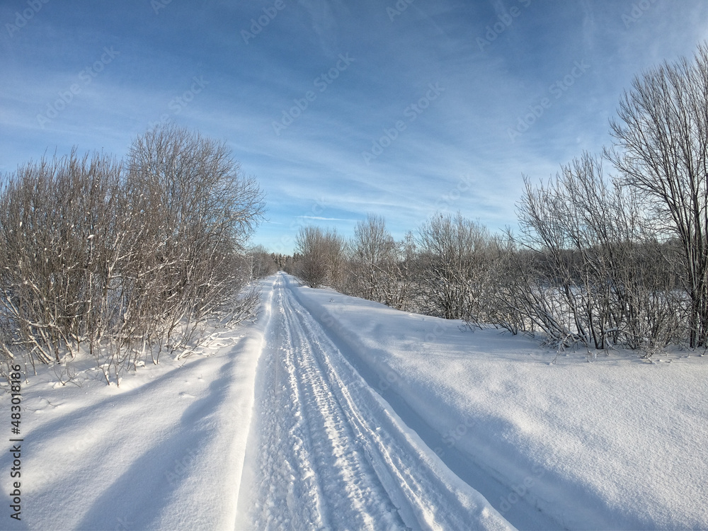 Countryside road through winter field with forest on a horizon Countryside road through winter field with forest on a horizon