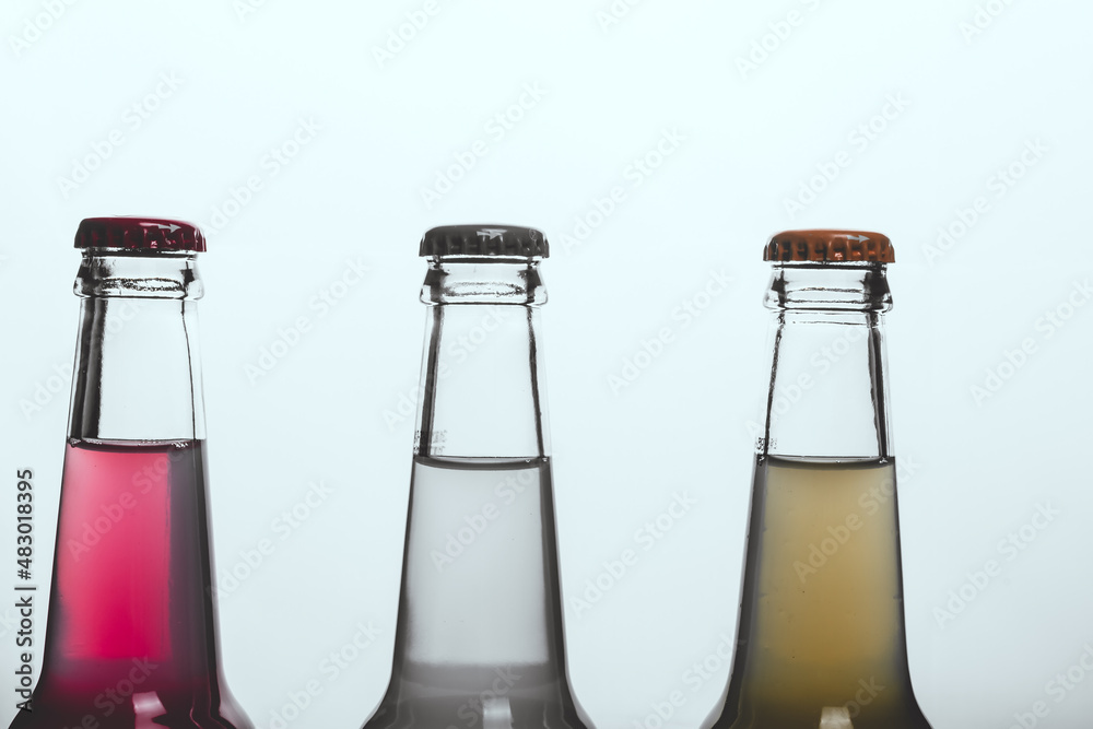 Three glass bottles with multicolored beer, drink, soda on a white background Three glass bottles with multicolored beer, drink, soda on a white background