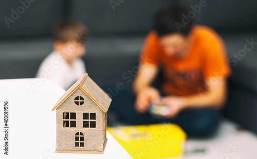 Father and son playing together on the background of wooden toy house