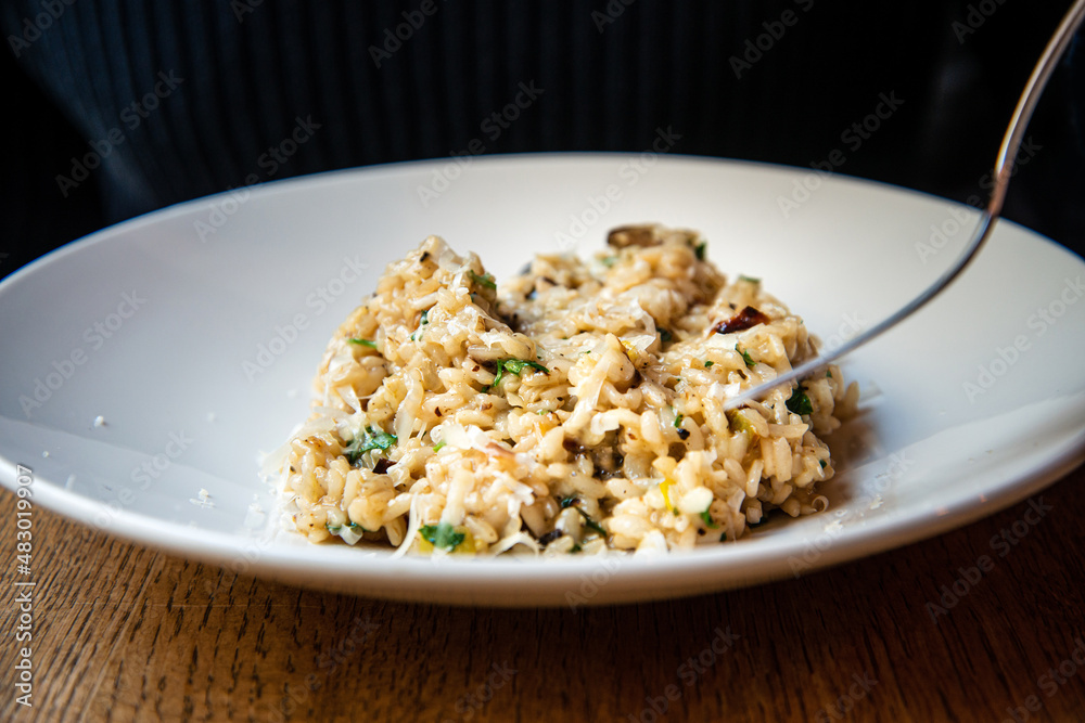 Delicious Italian vegetarian risotto cooked with mushrooms and onions served in white plate. Delicious Italian vegetarian risotto cooked with mushrooms and onions served in white plate.