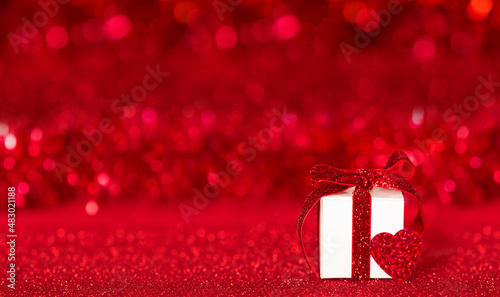 Romantic Valentine's Day. Gift box and red heart on red bokeh