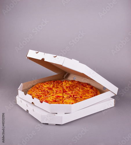 Two fragrant tasty pizzas in a box on gray background
