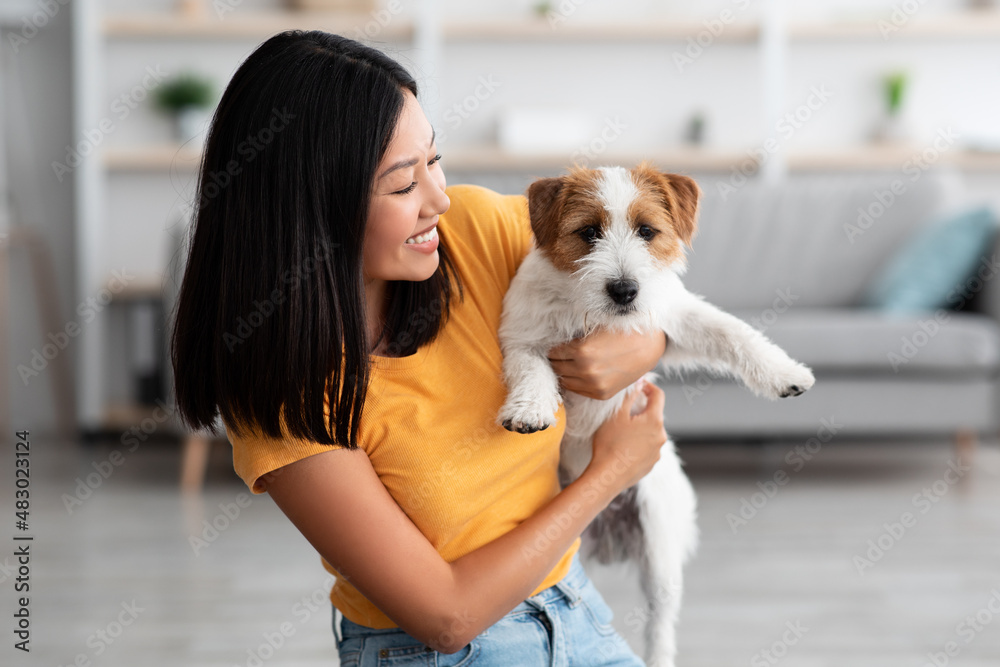 Happy asian woman holding her cute dog at home