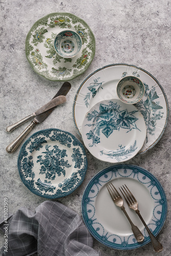 antique ceramic vintage plates and cutlery on a gray textured background