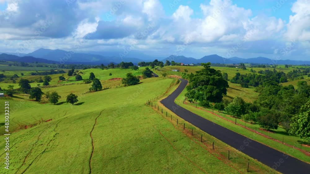 Empty Asphalt Road Through Green Hills At Daytime In Atherton, Tablelands, Australia. - aerial pullback Empty Asphalt Road Through Green Hills At Daytime In Atherton, Tablelands, Australia. - aerial pullback