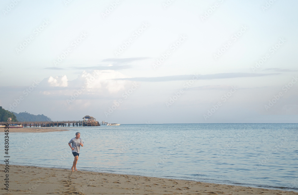 barefoot senior man running on the beach in the early morning barefoot senior man running on the beach in the early morning