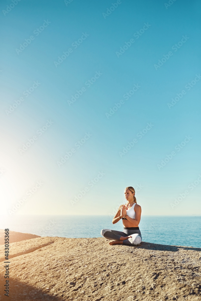Everyone should practice yoga. Shot of a young woman doing yoga at the beach.