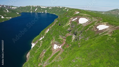 Aerial panorama. Drone flight along green hills shoreline by blue water lagoon