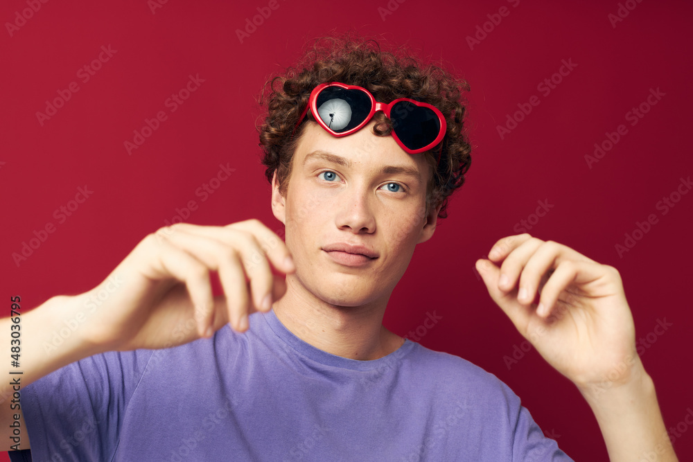 Young curly-haired man hand gestures heart shaped glasses posing isolated background Young curly-haired man hand gestures heart shaped glasses posing isolated background