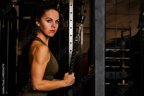 A beautiful woman in the gym exercises the triceps muscle on the pulley