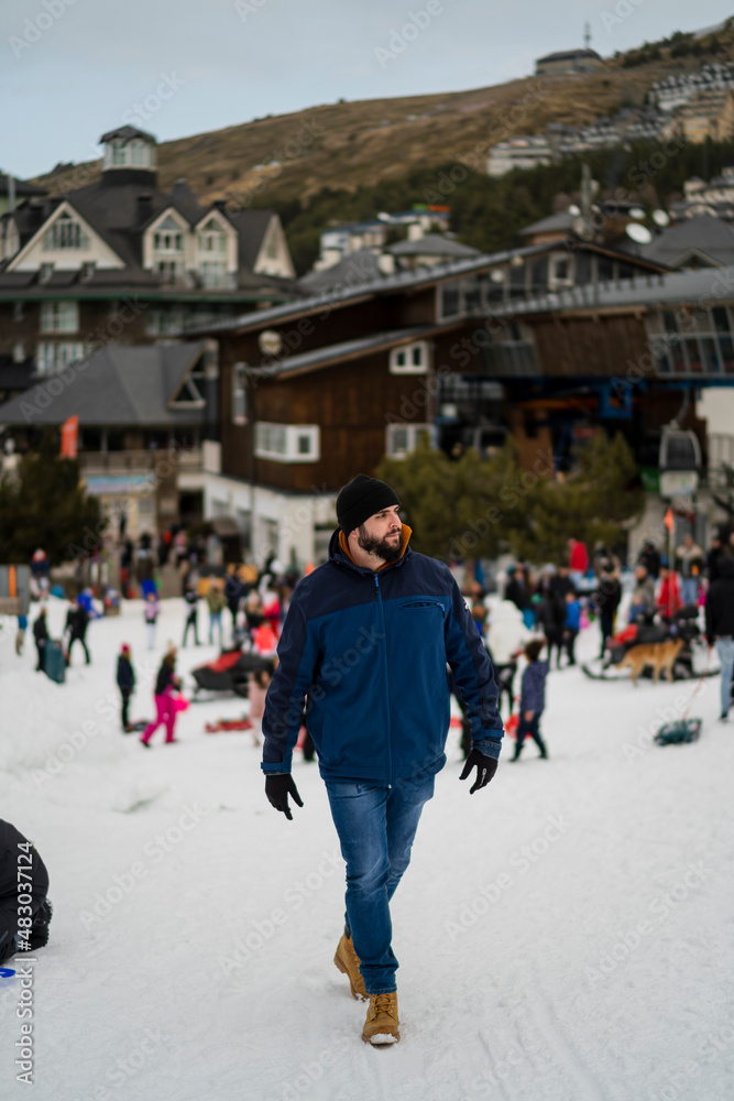 Chico alto con barba posando en la nieve y tomandose fotos en un entorno invernal