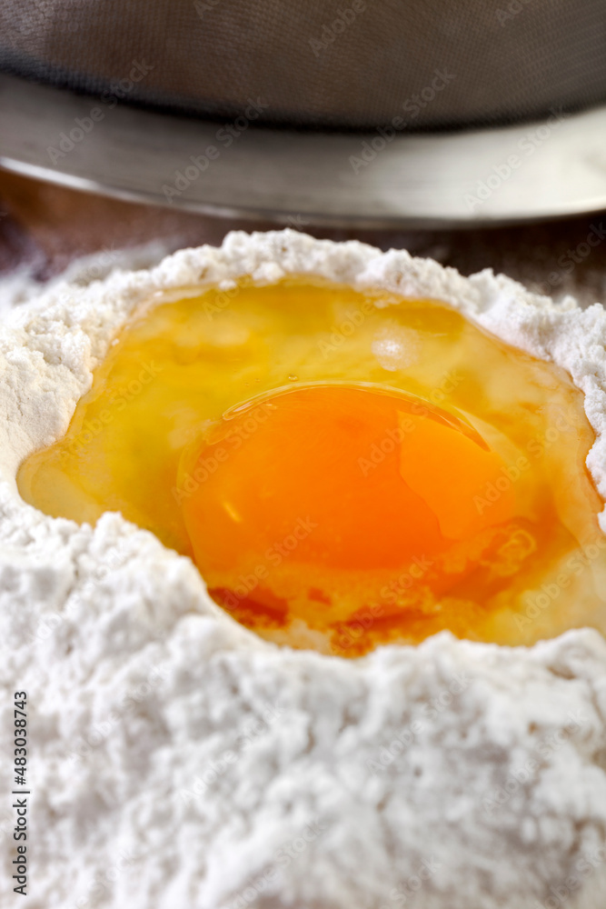One Egg in Flour on Wooden Table Surface One Egg in Flour on Wooden Table Surface