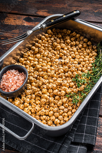 Vegetarin snack fried spicy chickpeas in a kitchen tray. Wooden background. Top view photo