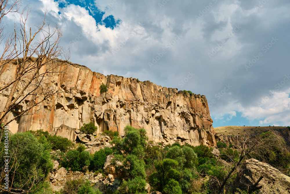 Canyon photo, sun reflection and cloudscape over huge stone of canyon in ihlara valley, turkey.