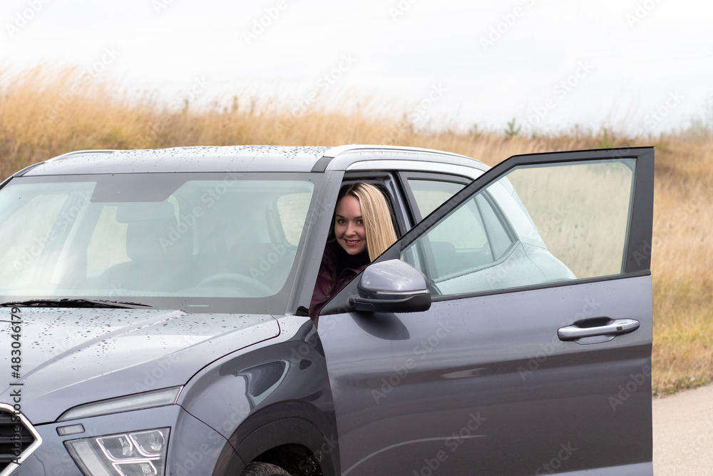 A woman driving a new dark gray car	