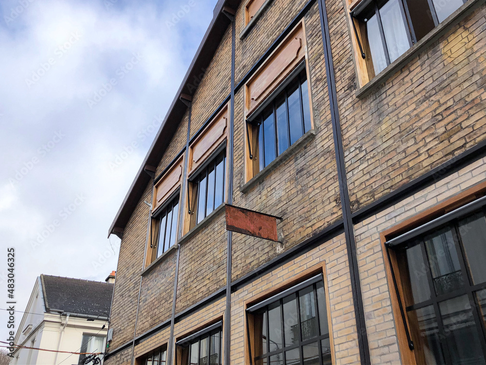 Architecture d'une façade d'un bâtiment ancien fait de briques, type hangar ou usine réhabilitée avec grandes fenêtres. Architecture d'une façade d'un bâtiment ancien fait de briques, type hangar ou usine réhabilitée avec grandes fenêtres.