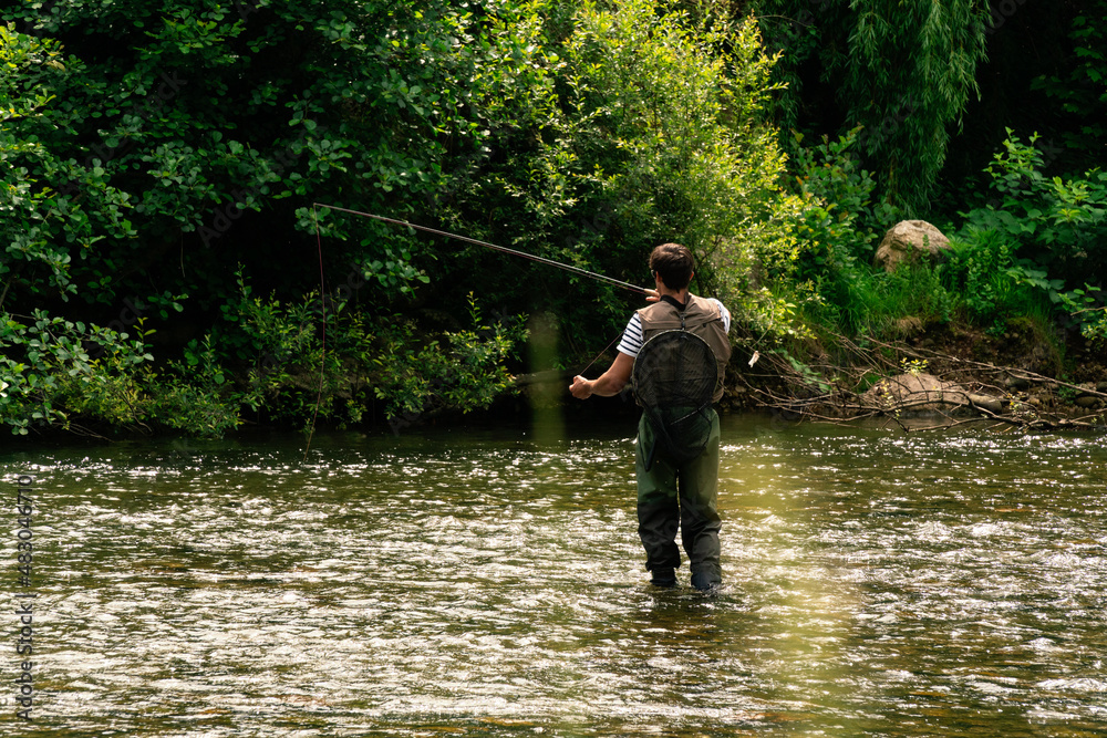 Young man fishing trouts in the river