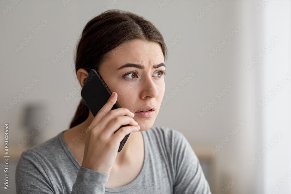 Portrait of worried anxious upset millennial lady talks by phone, received bad news at home Portrait of worried anxious upset millennial lady talks by phone, received bad news at home