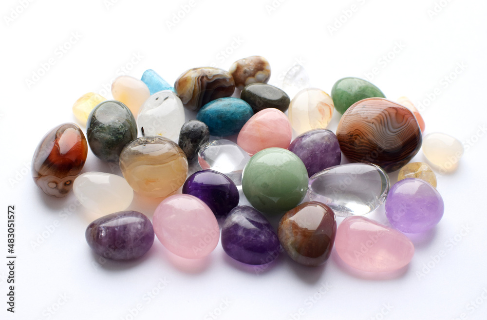 Gems of different colors. Amethyst, rose quartz, agate, apatite, aventurine, olivine, turquoise, aquamarine, rhinestone lie on a white background. Gems of different colors. Amethyst, rose quartz, agate, apatite, aventurine, olivine, turquoise, aquamarine, rhinestone lie on a white background.