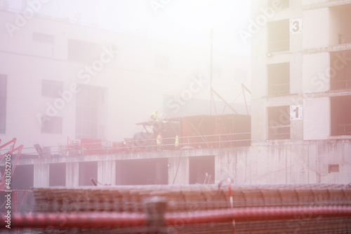 Multi-storey house construction process, builders are building a residential building on a foggy autumn morning. Construction process concept