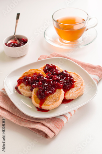 Syrniki, Cottage cheese or ricotta fritters served  jam on a white background, top view, a place to copy. Sweet food of Russian, Ukrainian cuisine