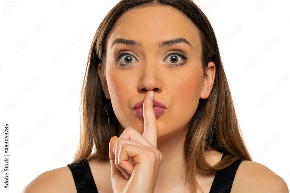 portrait of a beautiful woman with a finger in front of her lips portrait of a beautiful woman with a finger in front of her lips