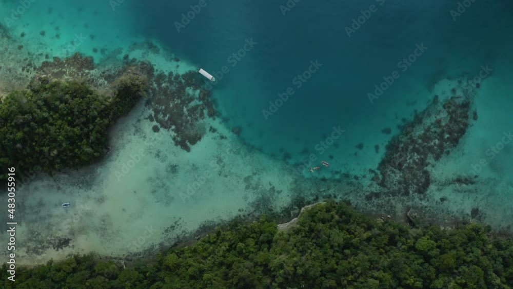 Recreational boat over clear and turquoise tropical water besides a stunning South Pacific island Recreational boat over clear and turquoise tropical water besides a stunning South Pacific island
