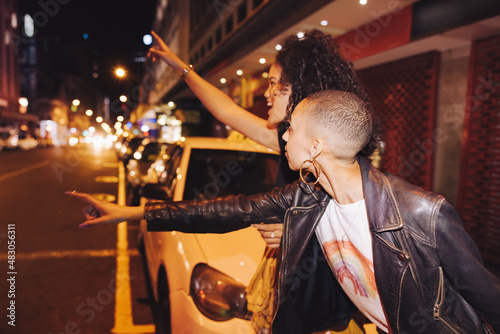 Two friends hailing a taxi in the city