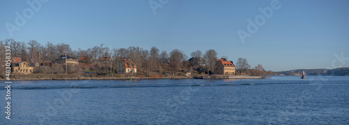 Panorama view of the ness Blockhusudden with old yellow 1700:s houses and a light house on a ground a sunny winter day in the archipelago of Stockholm © Hans Baath
