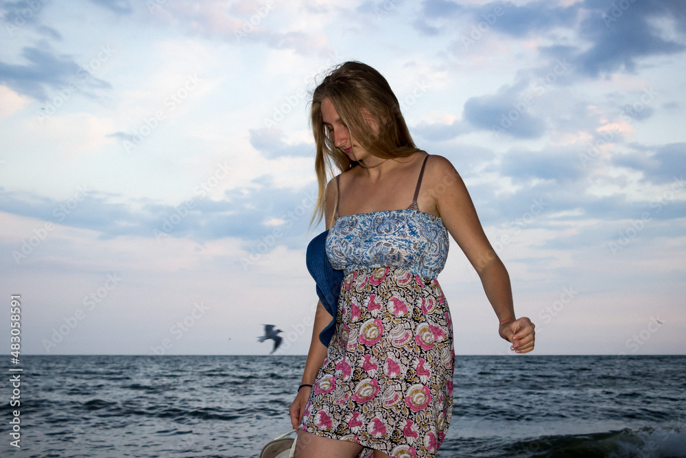 a young girl in the evening on the seashore in a sundress and with a hat a young girl in the evening on the seashore in a sundress and with a hat