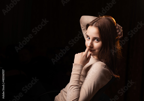 Portrait of a young woman on a dark background. The girl in the brown sweater. Friendly face looking at the camera. Place for text.