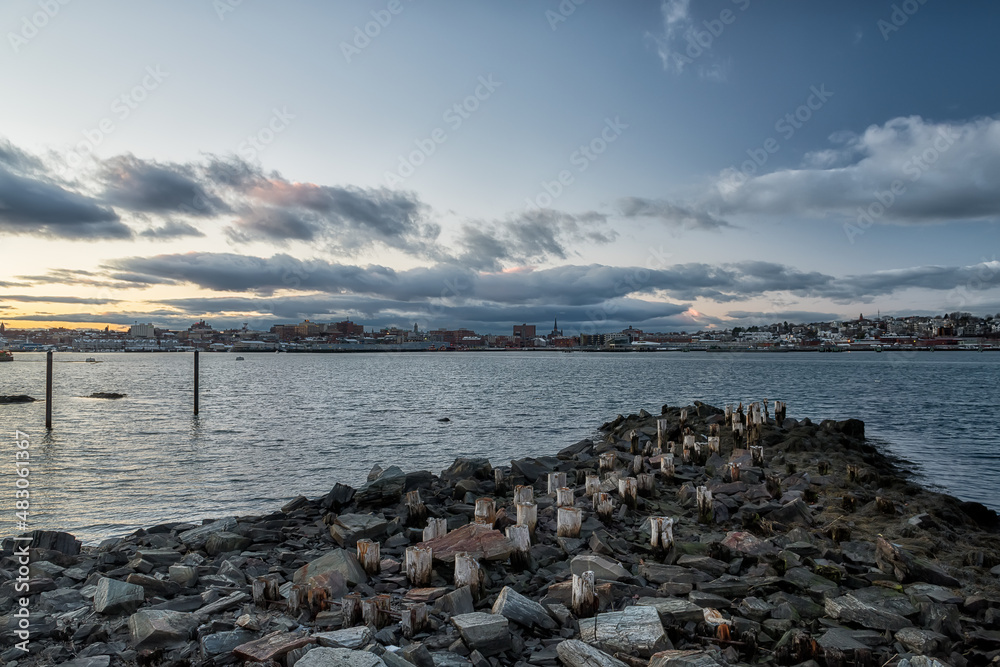 An old ruined pier in the bay and a view of the evening city. Portland. USA. Maine.
