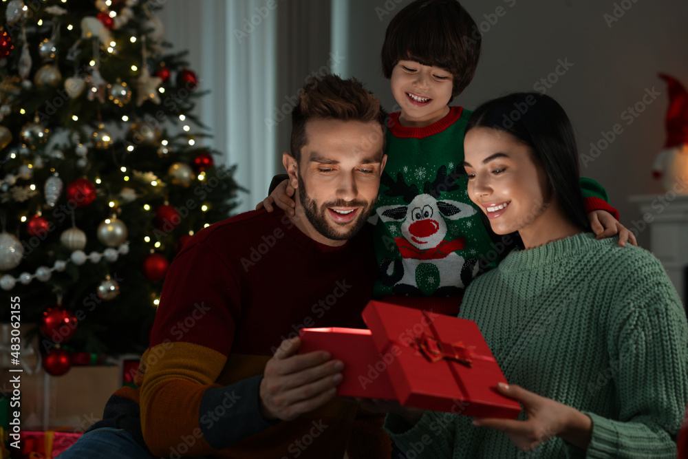 Happy family opening gift box with magical light at home. Christmas celebration Happy family opening gift box with magical light at home. Christmas celebration