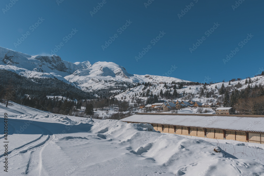 A picturesque view of a remote building in the snowcapped French Alps mountains on a cold winter day (L'Enclus, Devoluy)