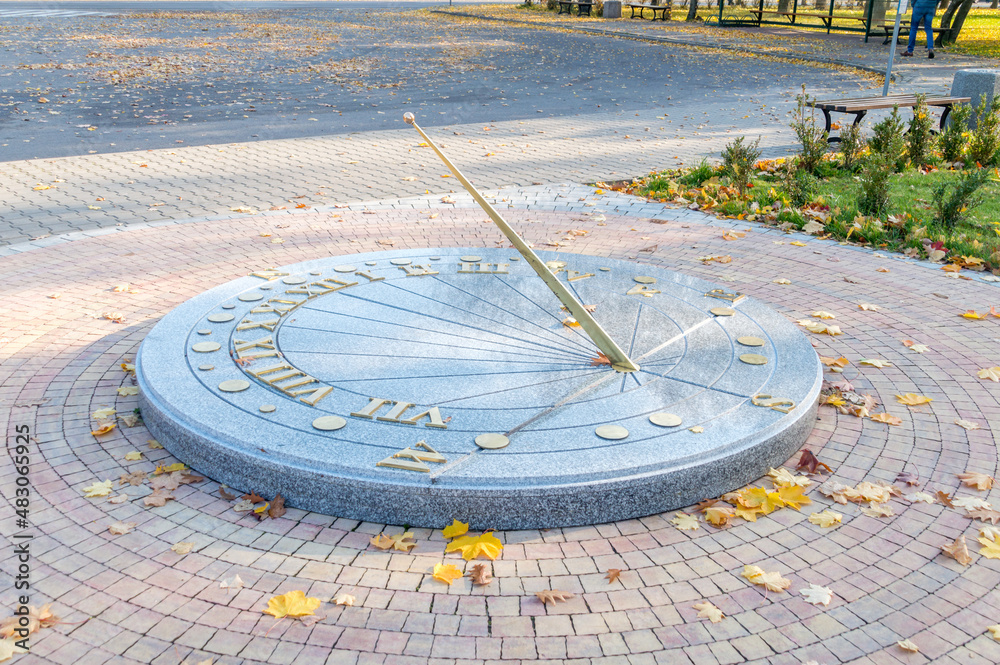 Sundial with autumn leaves in the park.
