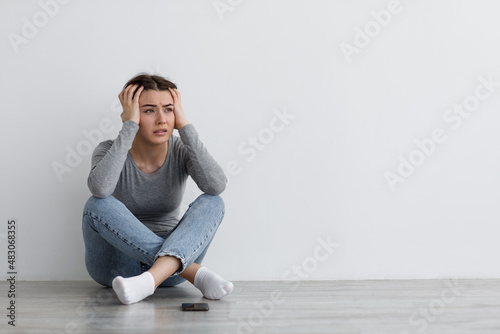 Despair anxious caucasian millennial lady sit on floor, suffering from depression, worried and received bad news