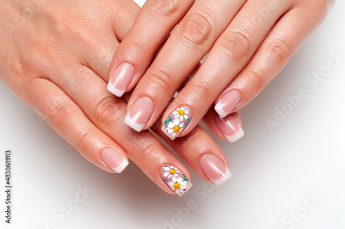 French manicure with painted daisies on long square nails close-up on a white background. Burnt hands.