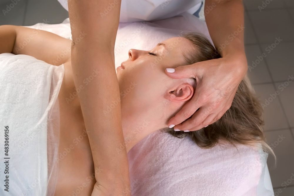 Cosmetologist is massaging ear and nech on woman's body in beauty clinic. Beautician making skincare and stimulation procedure. Spa treatment and massage in beauty salon. Cosmetologist is massaging ear and nech on woman's body in beauty clinic. Beautician making skincare and stimulation procedure. Spa treatment and massage in beauty salon.