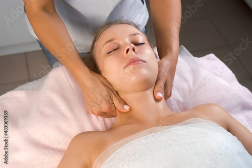 Massage therapist is massaging head  shoulders and neck to woman in cosmetology clinic. Beautician making skincare and stimulation procedure. Spa treatment and massage in beauty salon.