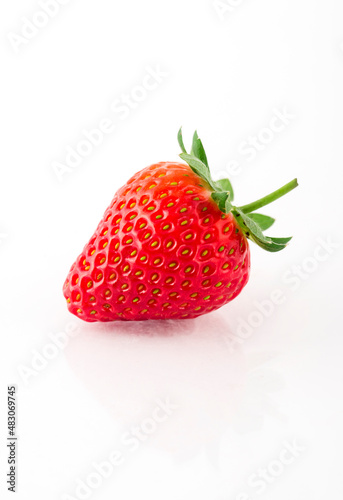 Fresh organic strawberries on a white reflective surface. Close up shot.