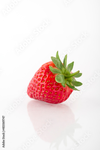 Fresh organic strawberries on a white reflective surface. Close up shot.