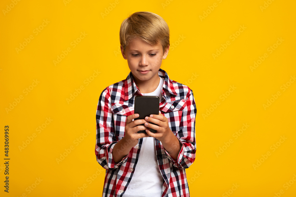 Busy european teen boy pupil typing on phone or playing on smartphone Busy european teen boy pupil typing on phone or playing on smartphone