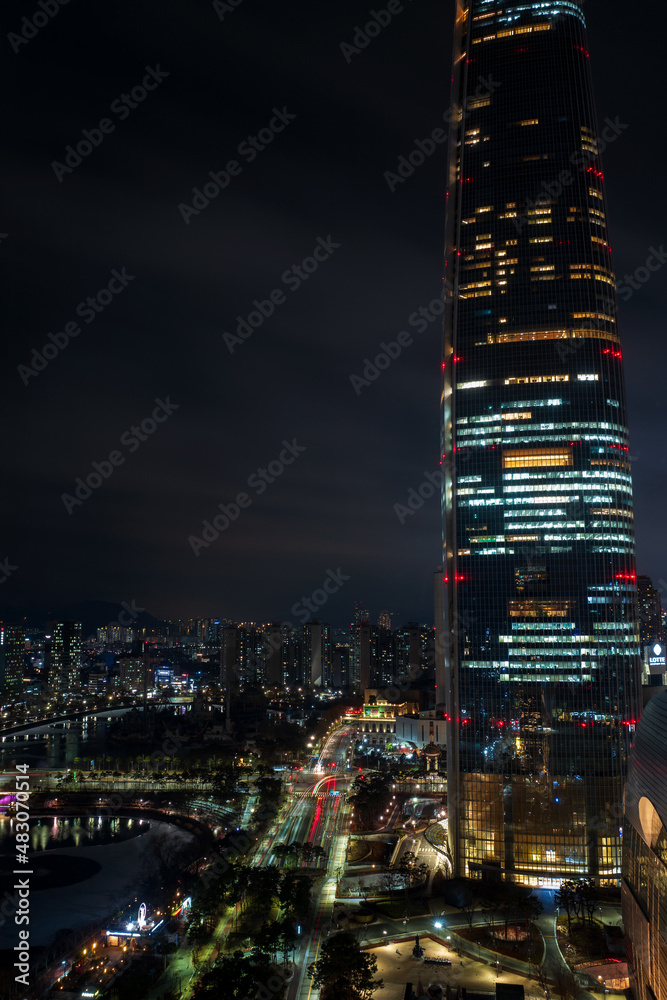 Obraz premium Jamsil buildings and Seokchon lake at night, Jamsil, Songpa-gu, Seoul, South Korea. Vertical view.