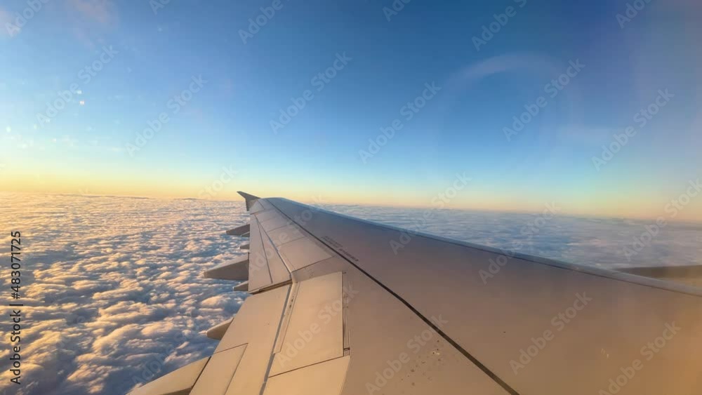 views from the window of an airplane in mid-flight, wing passing over the clouds take off