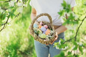 Easter egg hunt in spring garden. Funny teen girl with eggs basket and bunny ears on Easter egg hunt in sunny spring garden. Celebrating Easter. Happy easter card