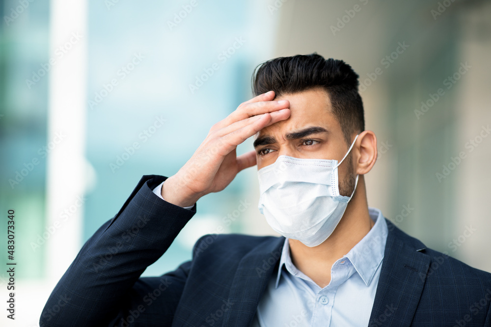 Stressful middle-eastern businessman in face mask touching head, business failure Stressful middle-eastern businessman in face mask touching head, business failure
